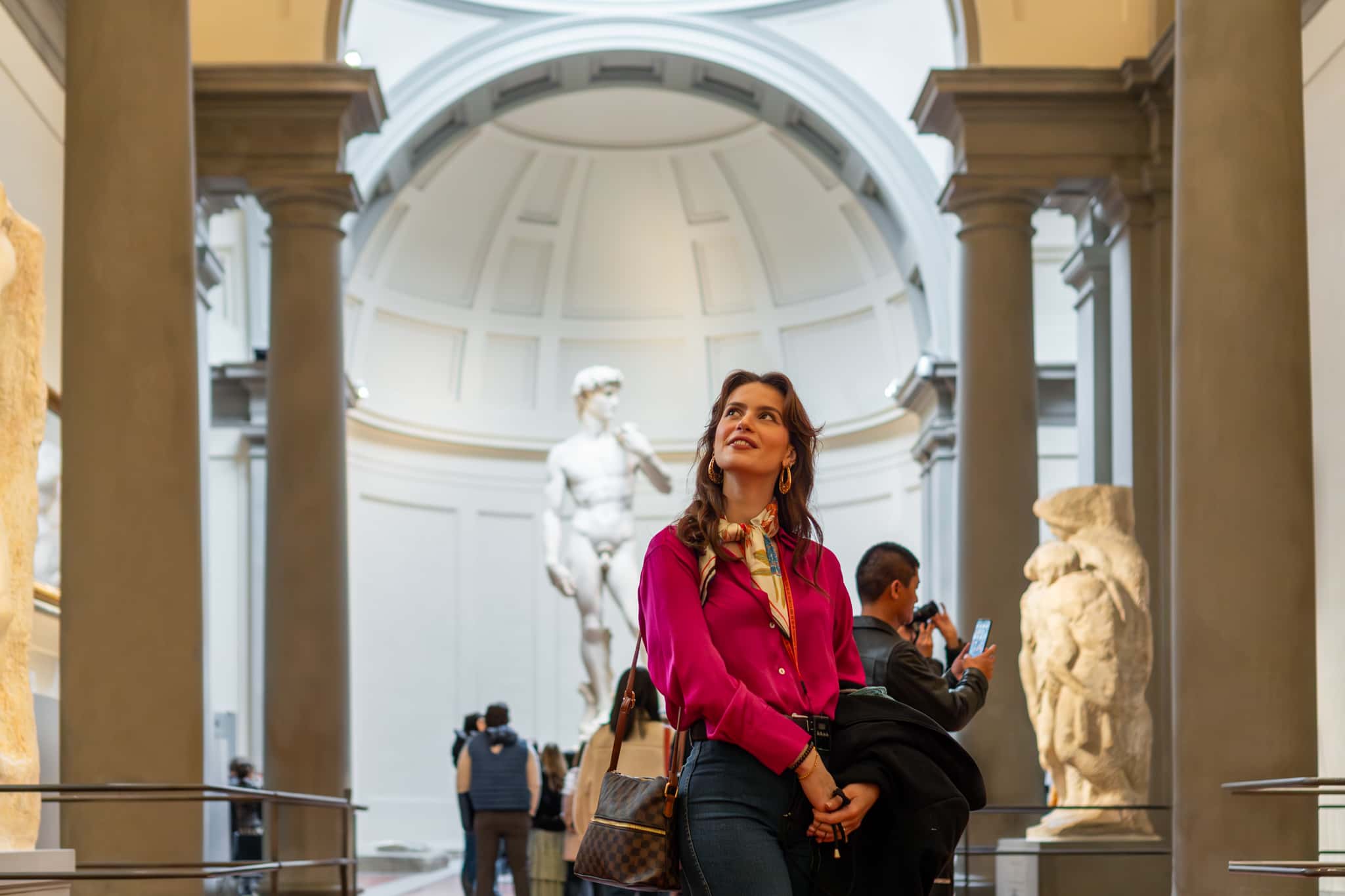 Woman in pink shirt with statue of david in background