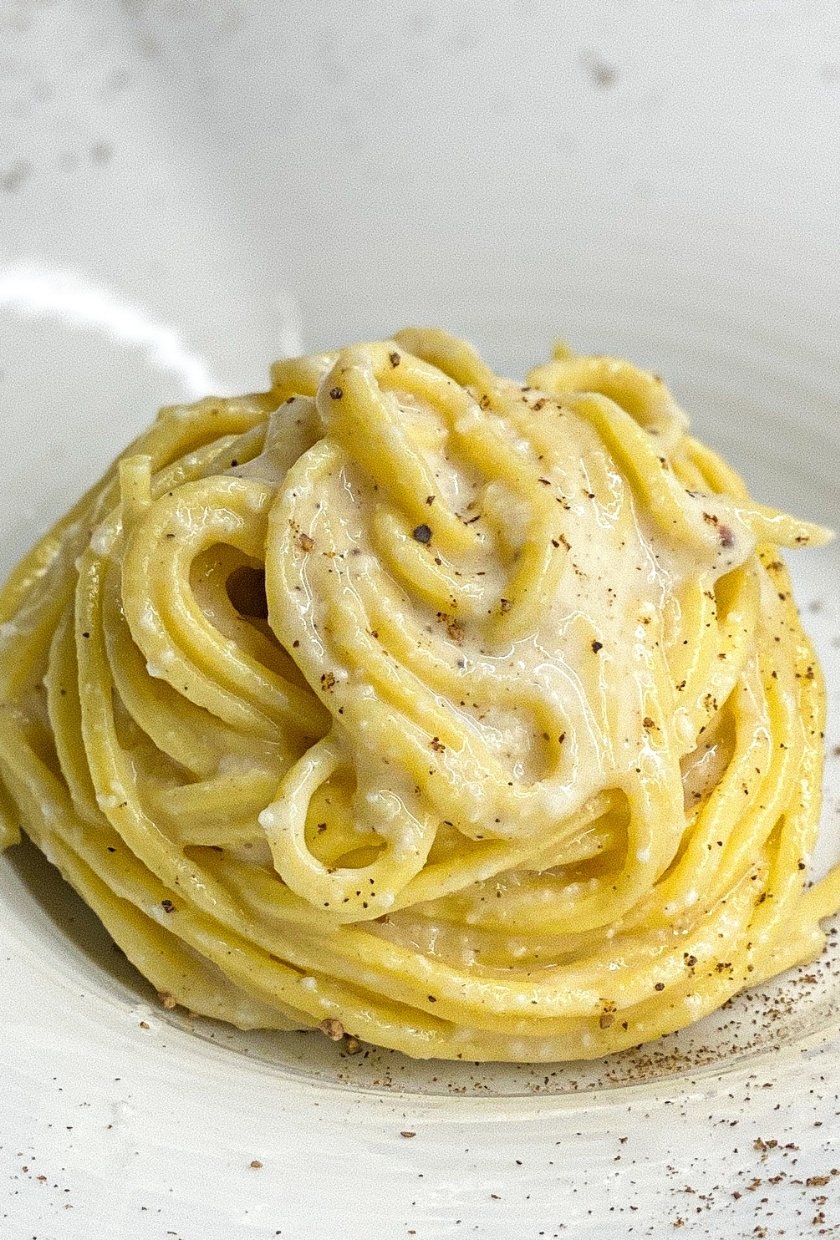 Pasta presented in a plate with white sauce on top