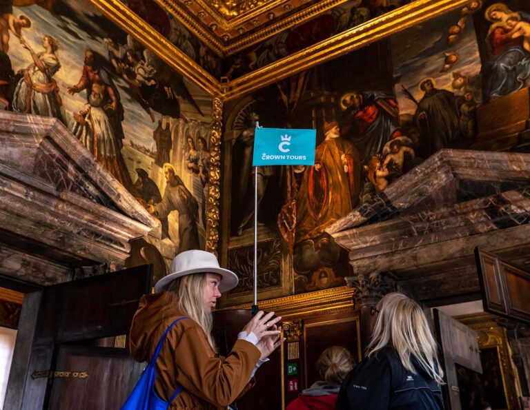 Doge's palace hall with grand paintings and tourists